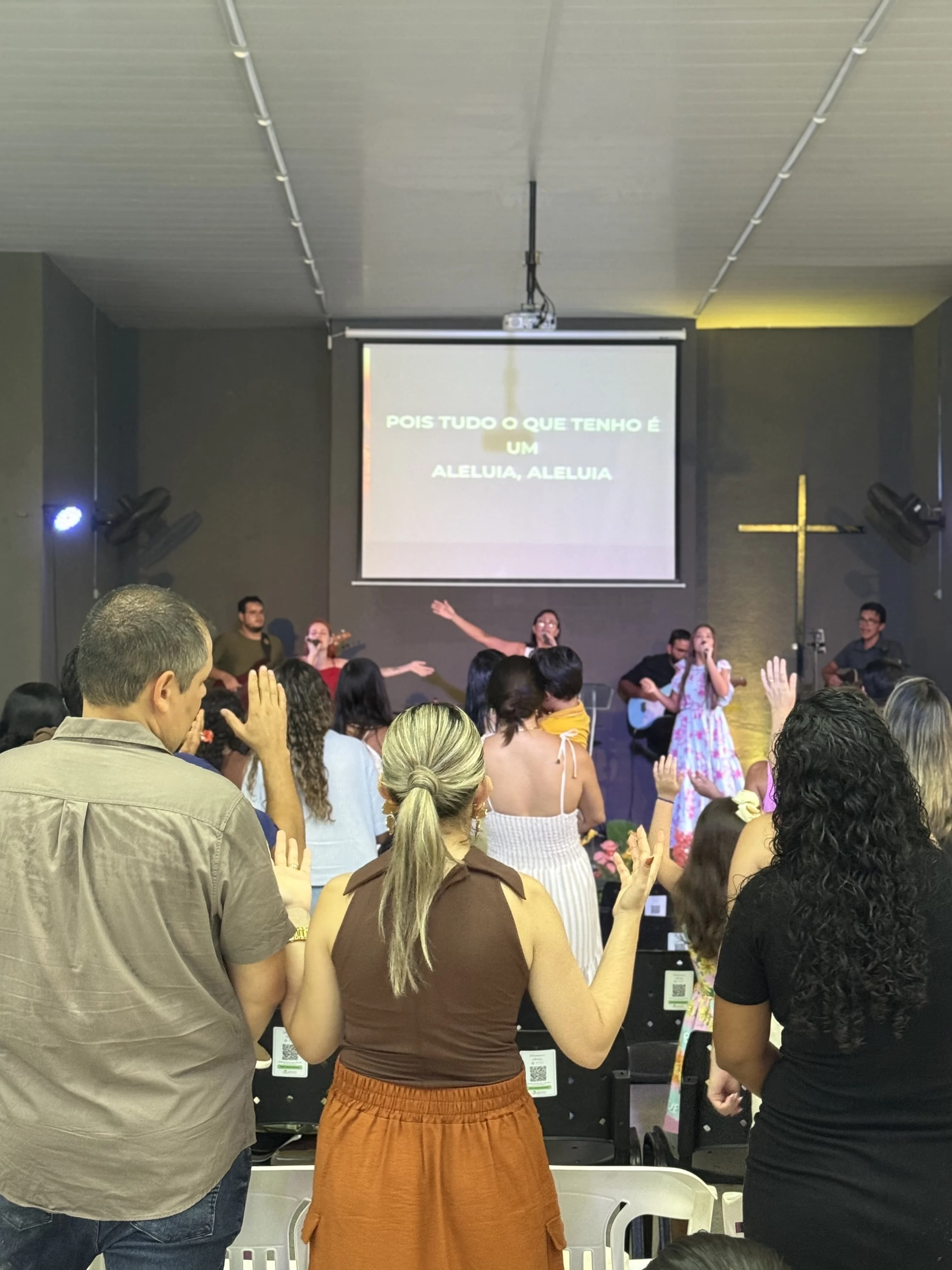 Foto mostrando um culto presencial na igreja com pessoas em adoração